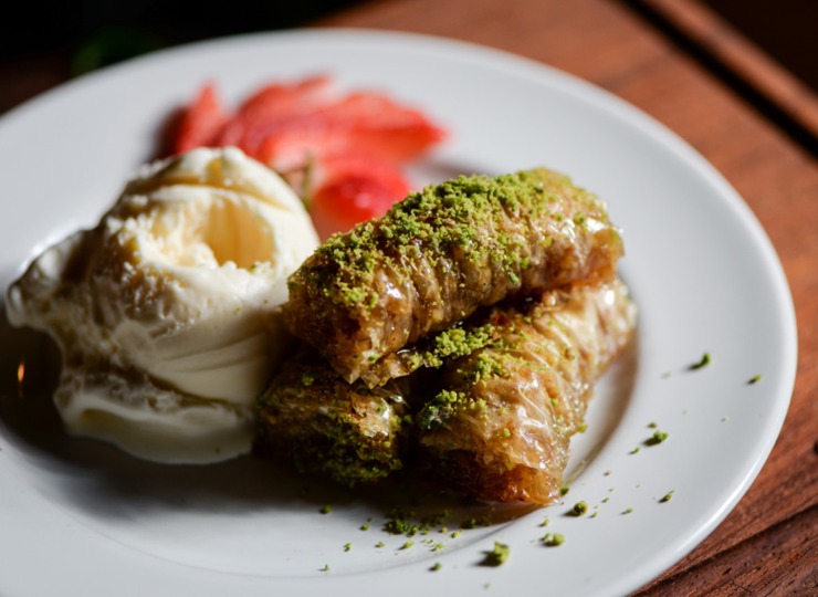 Baklava with vanilla ice cream garnished with out of focus strawberries