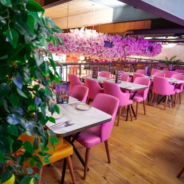 Best Turkish Mediterranean restaurant in the Theatre District Milton Keynes tables at Sultans, with green plant in the foreground and pink flowers hanging from the ceiling